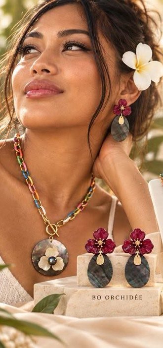 Une femme porte le collier médaillon multicolore et les boucles Orchidée rouges de Miliani